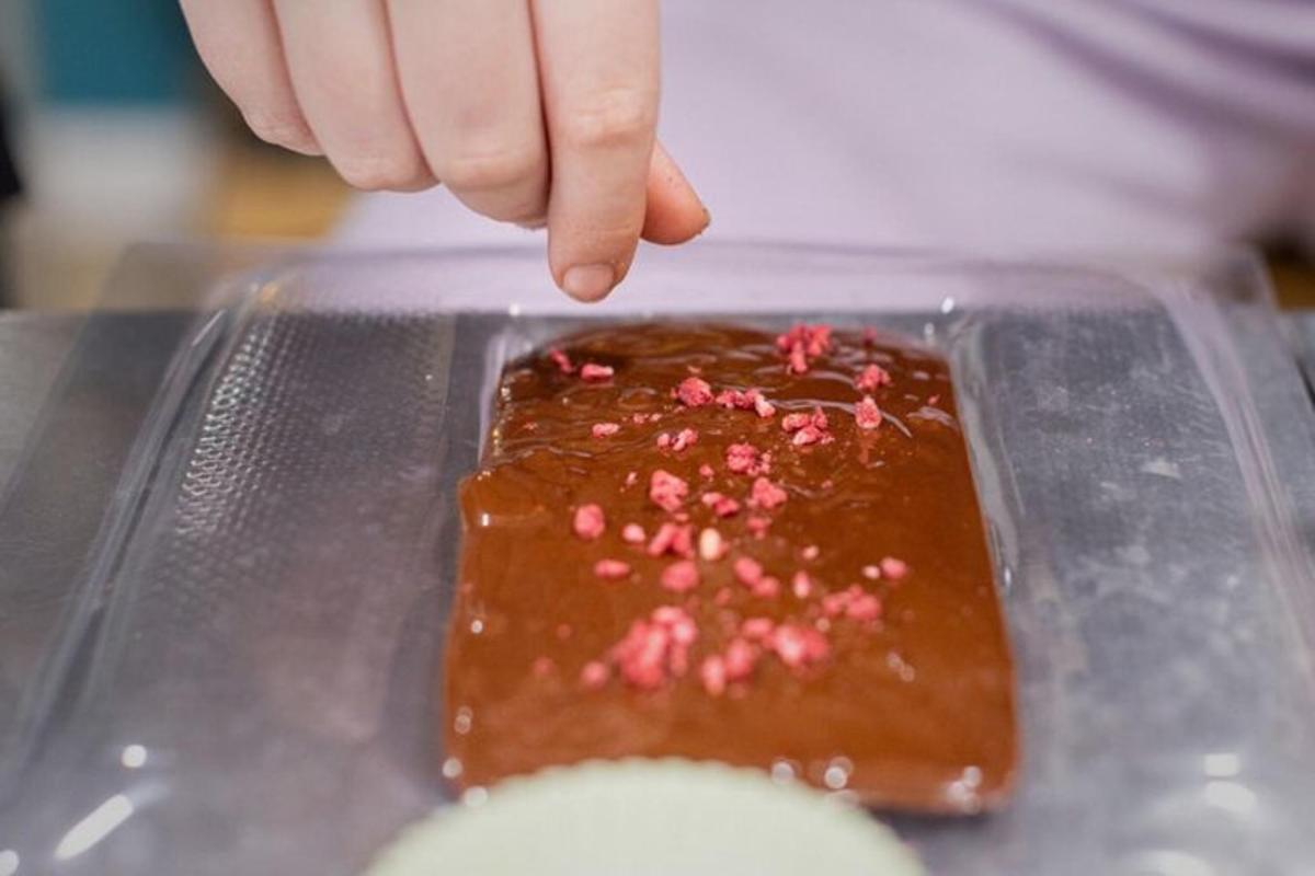 a hand reaching for a chocolate dessert with pink sprinkles