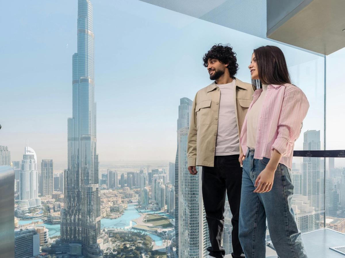 a man and a woman standing on top of a skyscraper