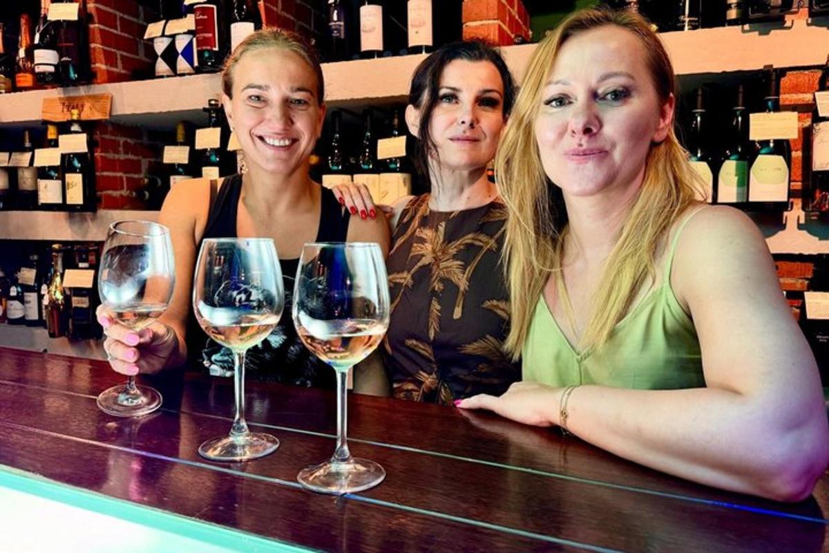 three women standing at a bar with wine glasses