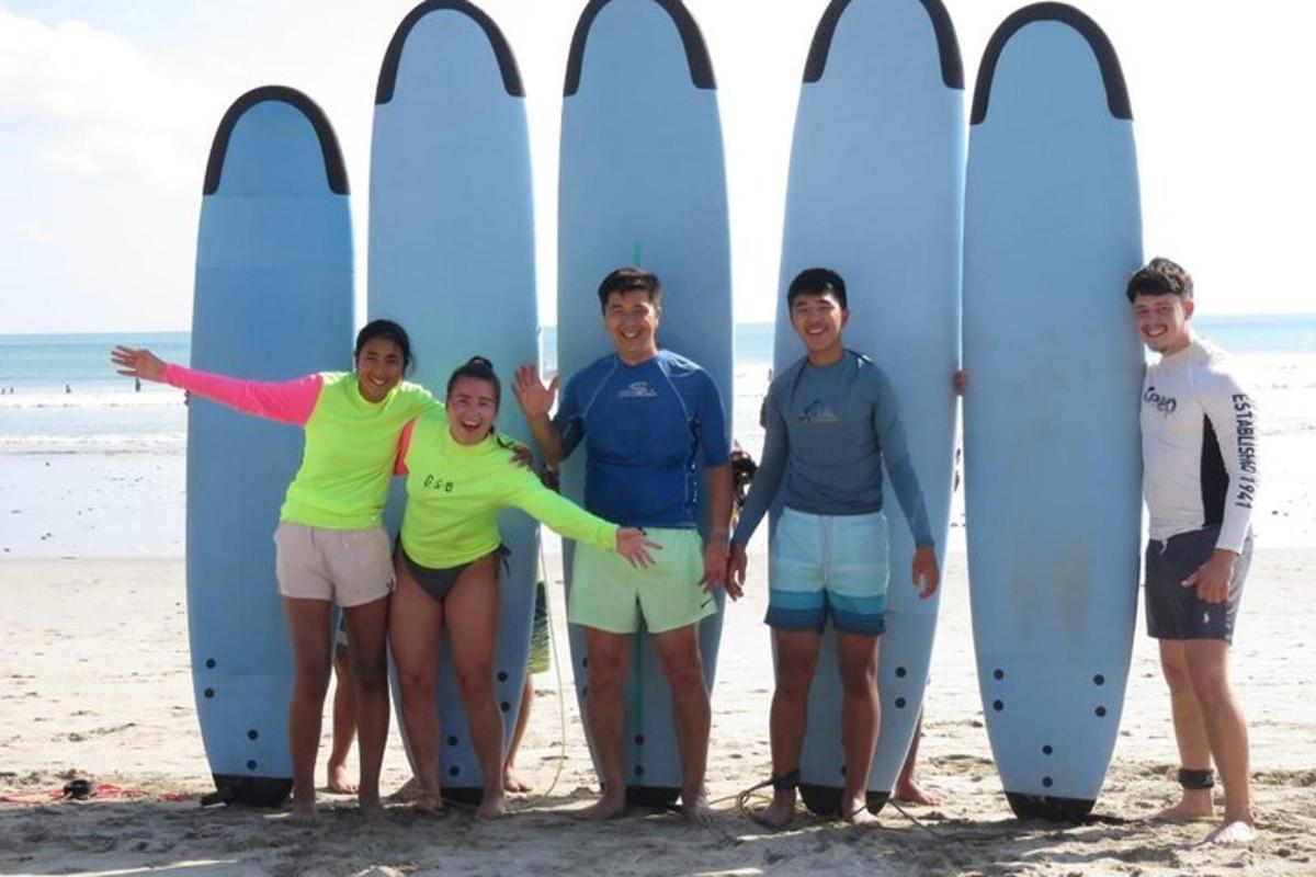 a group of people standing next to surfboards on the beach