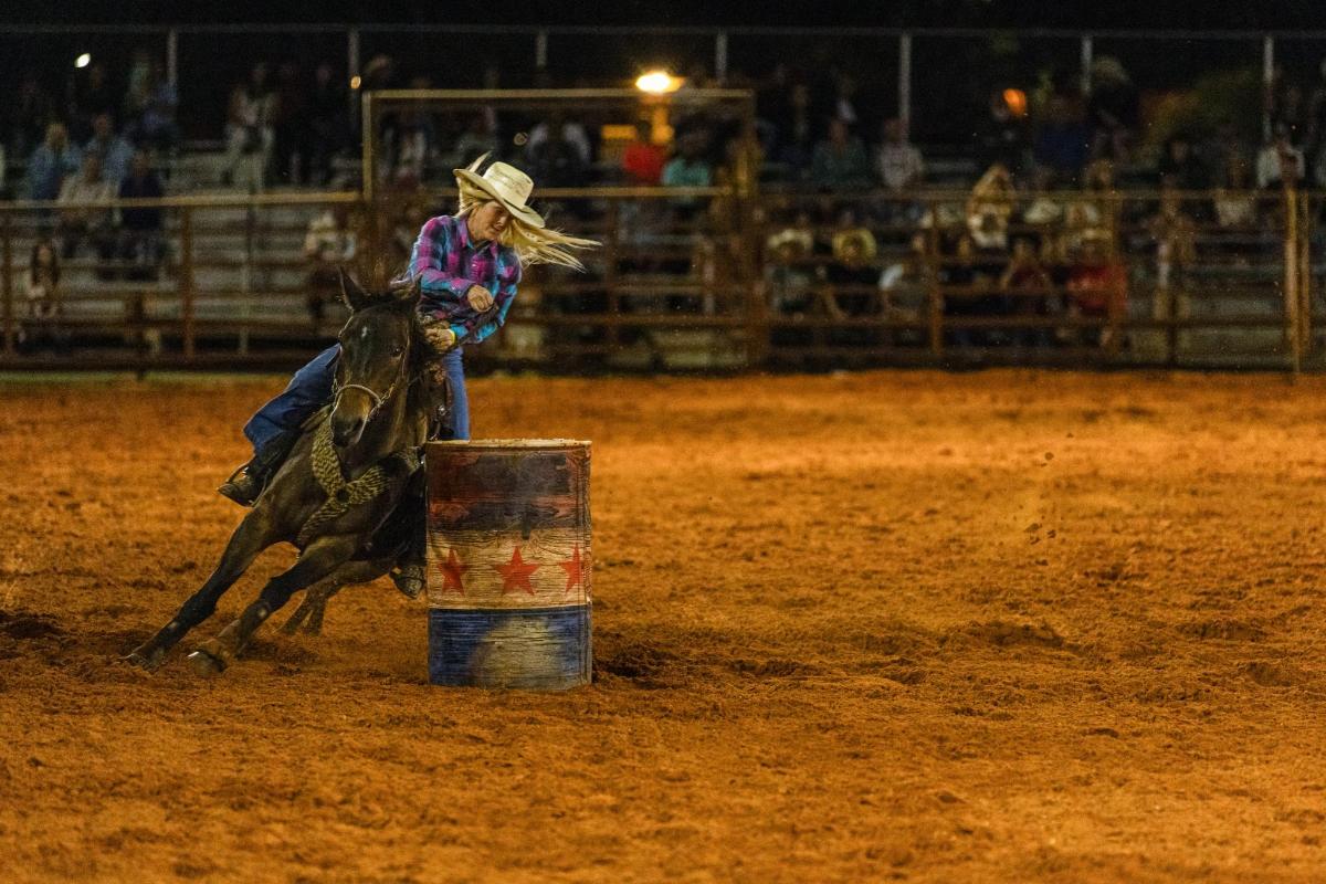 a woman riding a horse in a rodeo