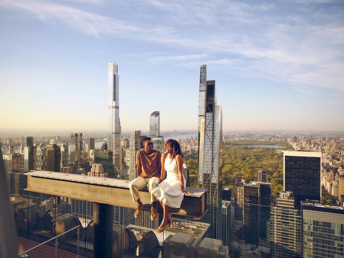 a man and a woman sitting on the edge of a building