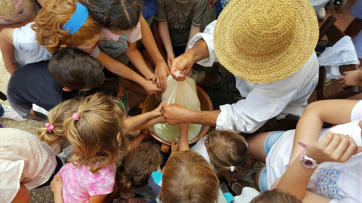 a group of children standing around a man holding a bucket