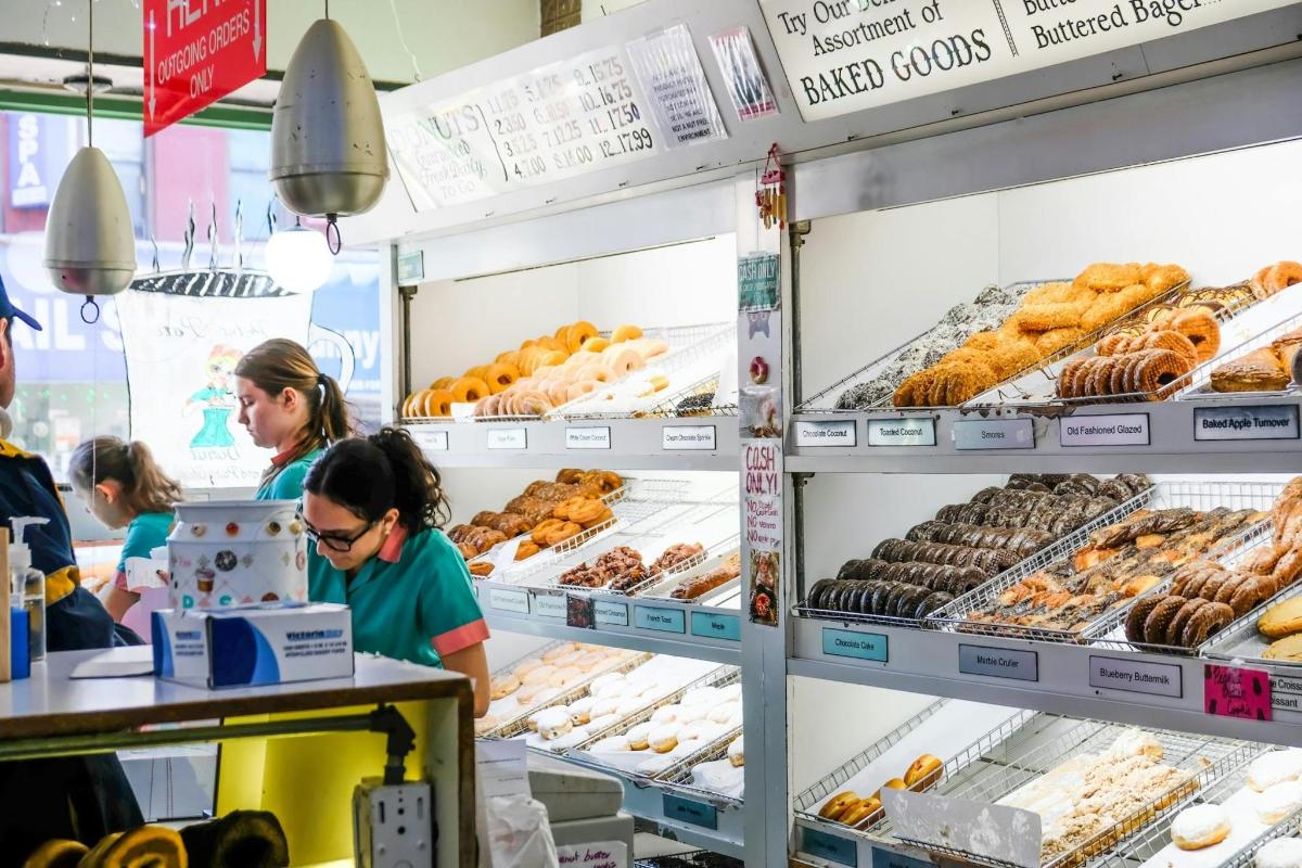 a group of people standing in a bakery selling donuts