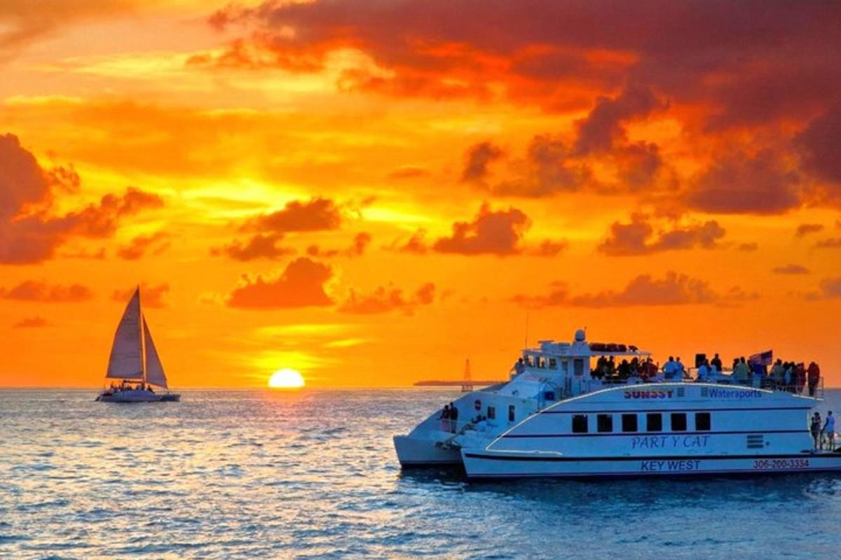 a cruise ship and a sailboat in the ocean at sunset