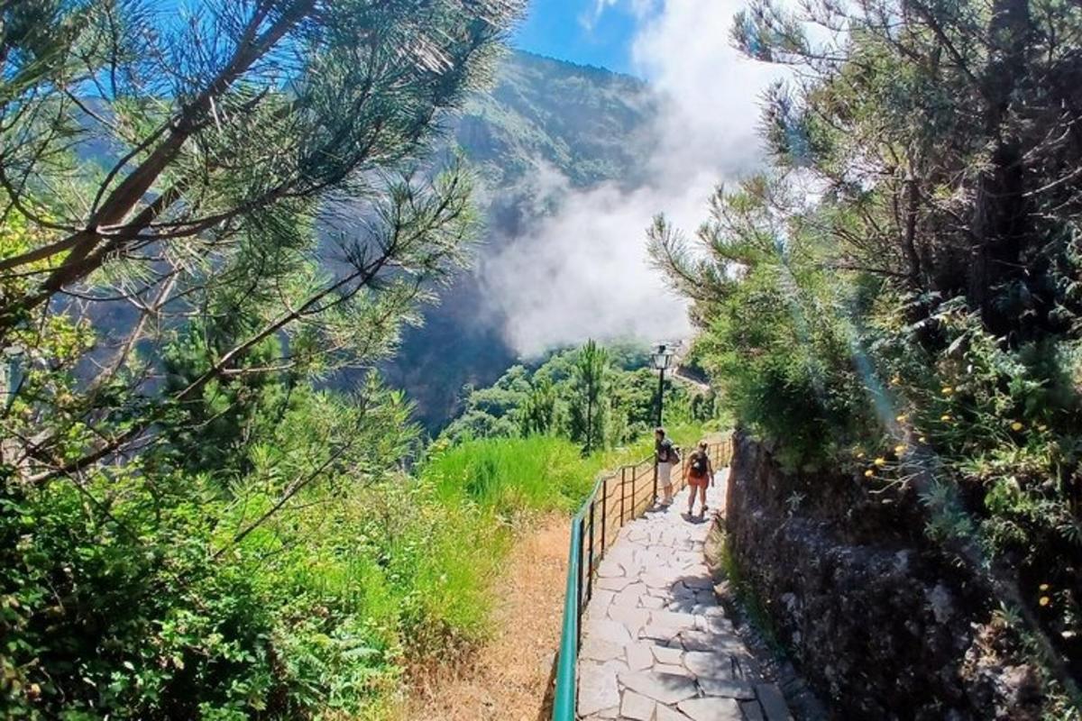 two people walking on a path in the mountains