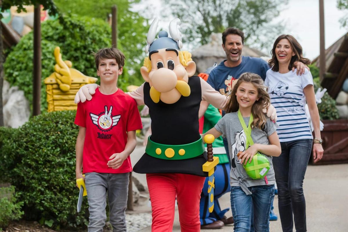 a family posing for a picture in front of a roller coaster