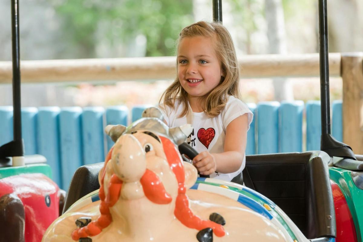 a little girl playing with a toy horse on a carousel