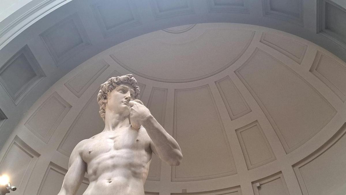 a statue of a naked man talking on a cell phone