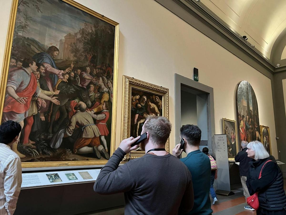 a man talking on his cell phone while looking at a painting