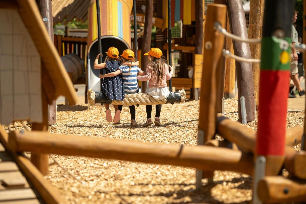 a group of three girls standing on a playground
