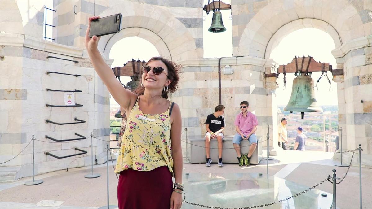 a woman holding up a cell phone in front of a building