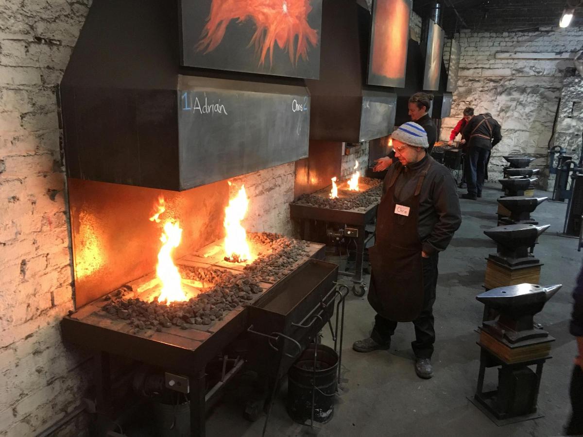 a man standing in front of a grill with fire
