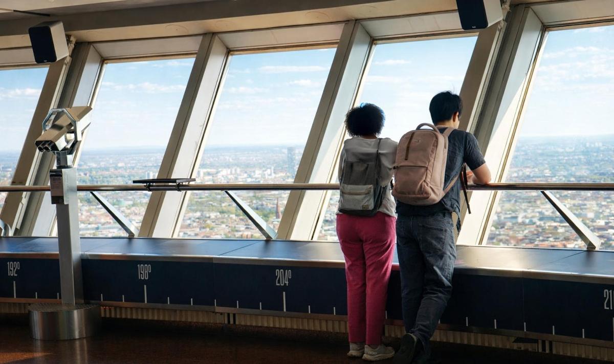 a man and a woman looking out at the city from the top of a tower