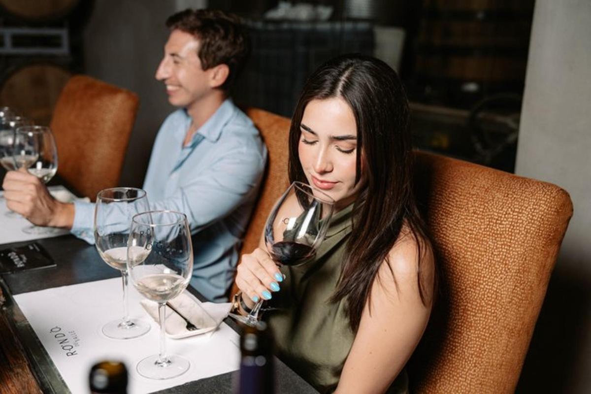 a woman sitting at a table drinking a glass of wine
