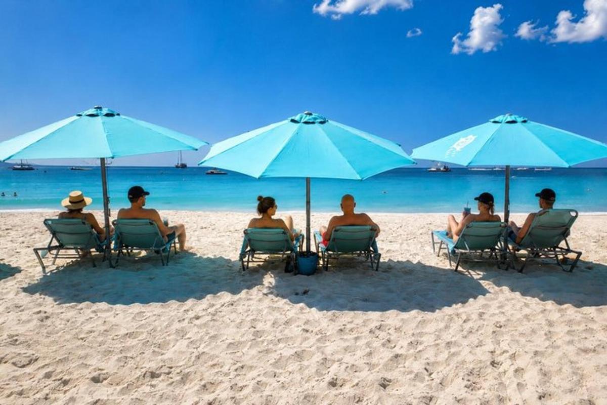 a group of people sitting in chairs under umbrellas on a beach