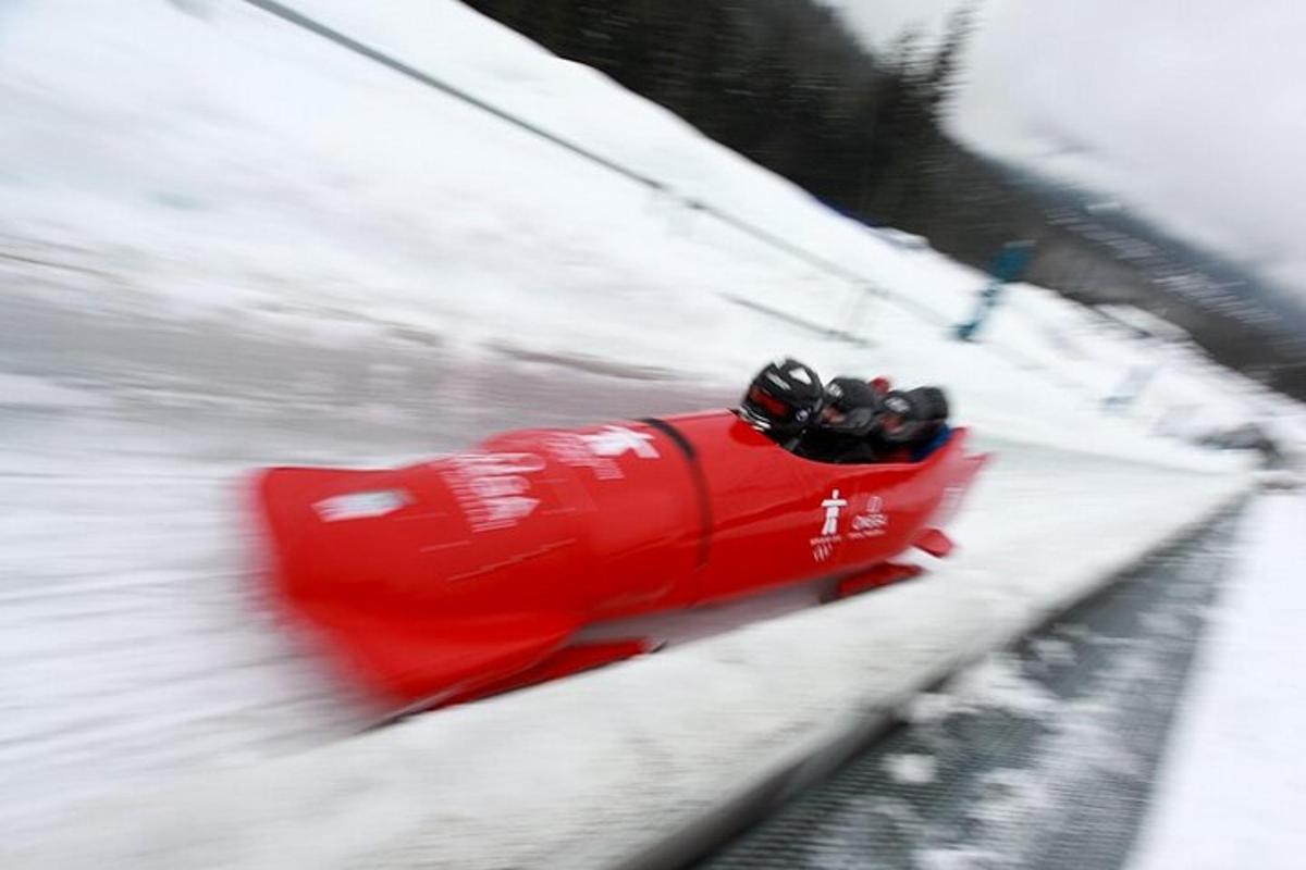 a red snowmobile is speeding down a snow covered slope