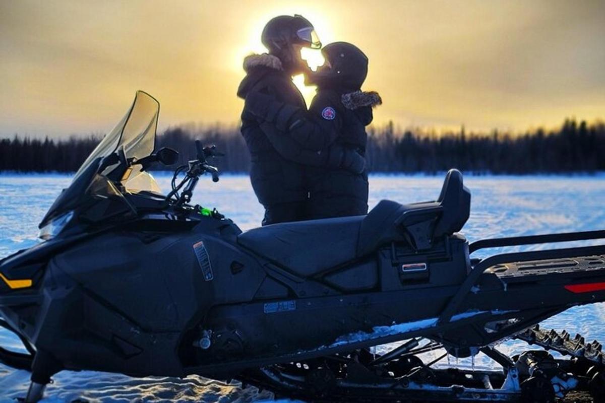 two people standing next to a motorcycle in the snow