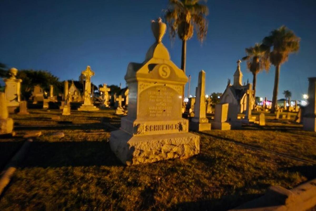 a monument in a cemetery at night with palm trees