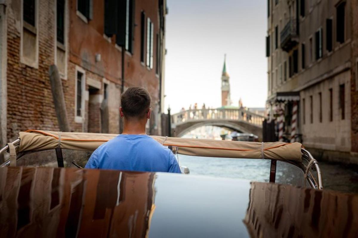 a man riding a boat in a canal with a bridge