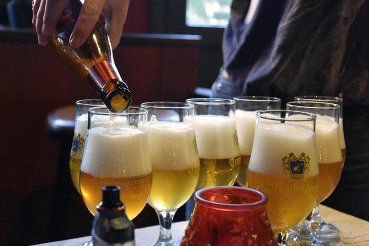 a person pouring beer into glasses on a table
