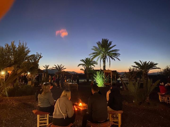 a group of people sitting around a fire at night